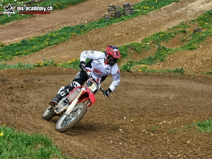 Fahrer legt sich in einer Erdkurve am Hang in Schräglage – Kurven fahren auf dem MX-Bike