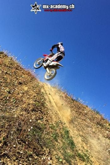 Downhill mal andersrum: Fahrer fährt einen steilen Hang hinauf, darüber blauer Himmel