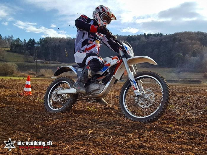 Fahrer auf einem E-Motocross Bike neben einer Pylone – Elektro Motocross fahren im Gelände