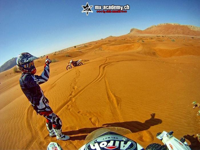 Freeride in der Wüste von Dubai: Fahrer reckt den Arm in die Höhe, hinter ihm Sanddünen