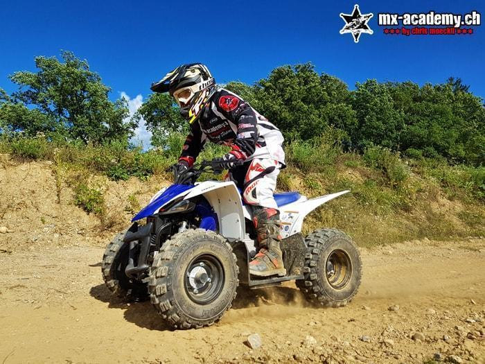 Junger Fahrer beim ATV fahren auf einem blauen Quad mitten im Gelände