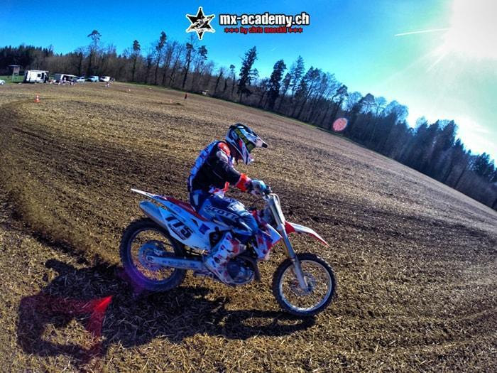 Dirt Track Feeling: Fahrer auf blauem Motocross-Motorrad driftet durch eine flache Kurve