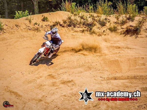 Action erleben in der Sandkurve: Das Hinterrad des Fahrers wirft eine Sandfontäne auf