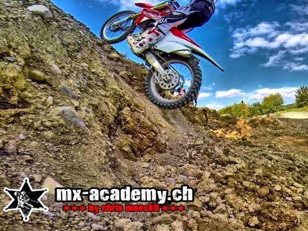 Offroad fahren im Steilhang: Fahrer zwischen Steinen, über ihm blauer Himmel und Wolken