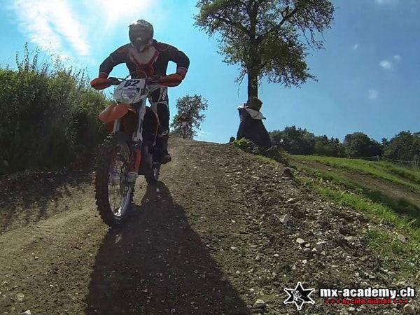 Auf einem Erdweg direkt Richtung Kamera: Fahrer mit orangem Offroad Motorrad im Gelände