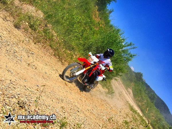 Fahrer auf einer roten Honda an einem steilen Erdhang, in schräger Aufnahme