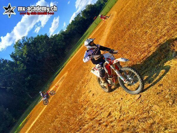 Offroad Kurs auf trockenem Boden: orangefarbenes Motorrad, der Horizont im Bild schräg