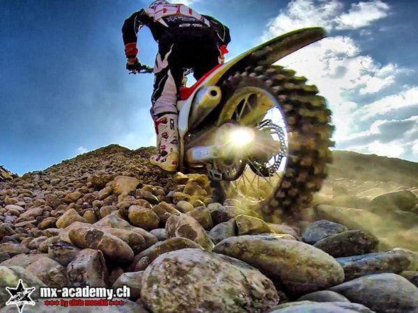 Enduro fahren im Geröll: Die Startnummer 50 rollt über grosse, runde Steine, von unten fotografiert