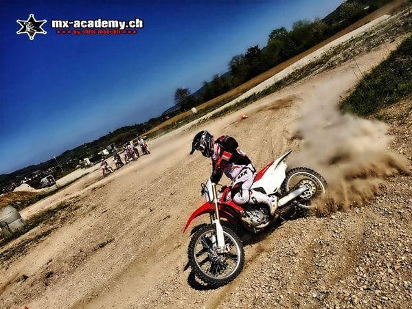 Wochenende Motocross: Fahrer zieht in der Kurve eine Staubwolke hinter sich her, andere warten