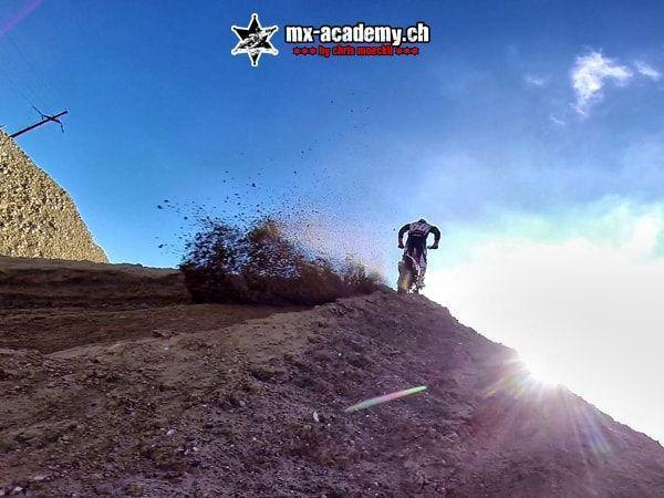 Action Sport im Gegenlicht: Fahrer auf einer Kuppe, aufgewirbelte Erde fliegt durch die Luft