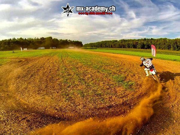 Fahrer mit Startnummer 50 zieht beim MX fahren in der Kurve eine Staubfahne über die Erdstrecke