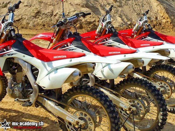 Mehrere Honda CRF stehen in einer Reihe vor einem Sandhügel – welches Motocross Motorrad passt für Anfänger?