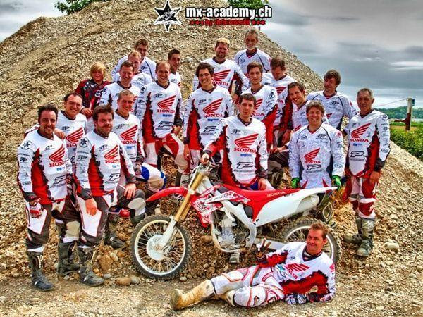 Event mit Motocross: grosse Gruppe in Honda-Trikots rund um eine Honda auf einem Schotterhügel