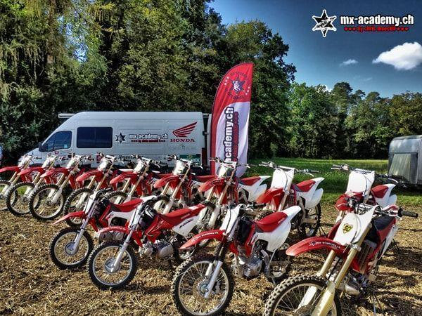 Honda-Motorräder für Erwachsene und Kinder aufgereiht vor dem MX-Academy-Transporter – Anfänger Motocross in jeder Grösse