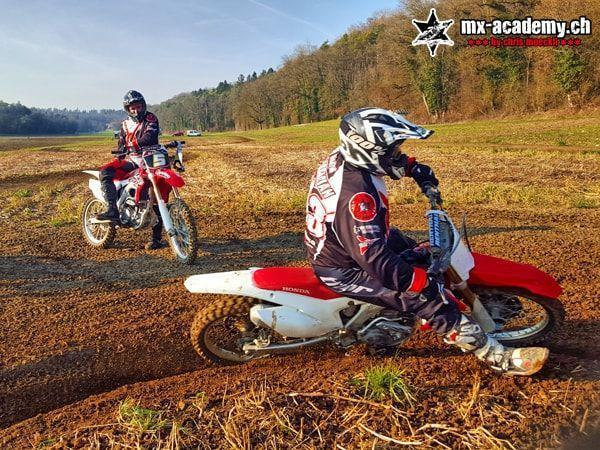 Zwei Fahrer üben auf ihren Honda-Motorrädern Kurven auf einer Erdfläche – Schnupperkurs Motorrad mit Übungen