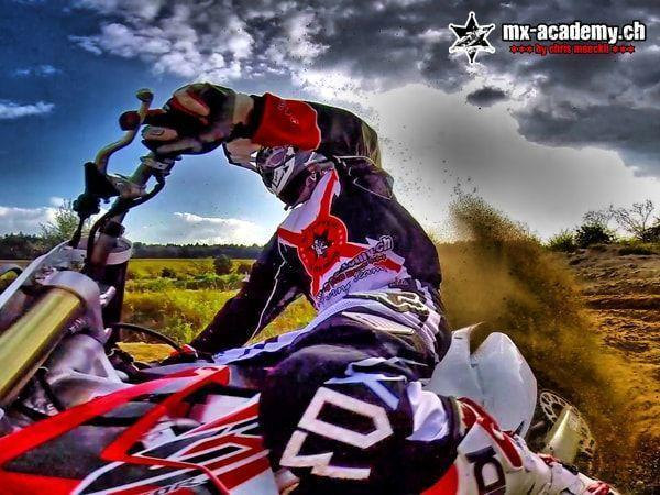 Driften lernen aus Fahrersicht: Weitwinkel vom Motorrad, der Fahrer legt sich in die Kurve, Erde spritzt