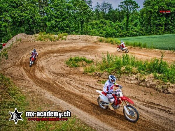 Motorsport Wochenende: drei Fahrer auf einer kurvigen Sandstrecke zwischen Wiese und Wald