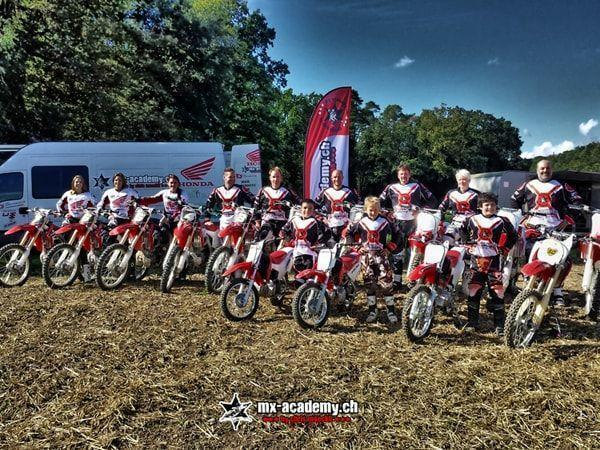 Gruppenbild mit Fahrerinnen, Fahrern und Kindern, dazu Honda-Motorräder vor dem Transporter