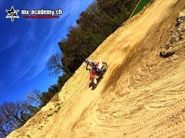 Fahrer an einem steilen Sandhang zwischen Bäumen, aus schräger Perspektive fotografiert