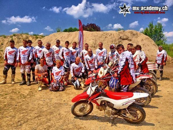 Motorsport Event: Gruppenfoto in Honda-Trikots mit den Motorrädern vor einem grossen Sandhügel