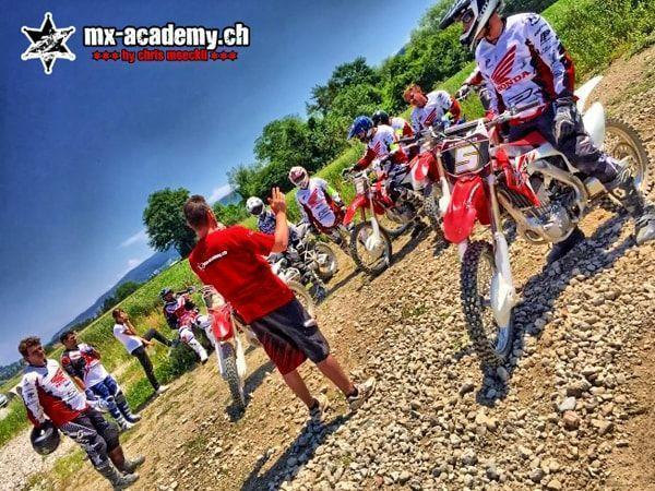 Trainer im roten T-Shirt erklärt der Fahrergruppe neben ihren Hondas die nächste Übung