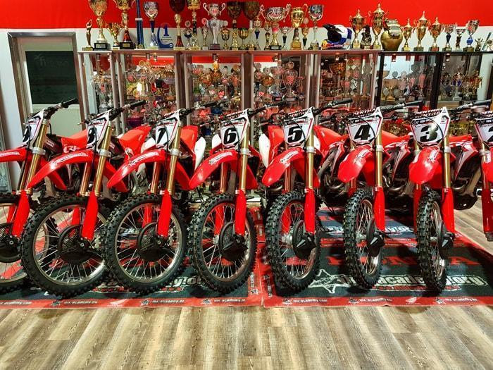 Motocross kaufen: Reihe roter Honda-Motocross-Motorräder nebeneinander im Shop der MX-Academy