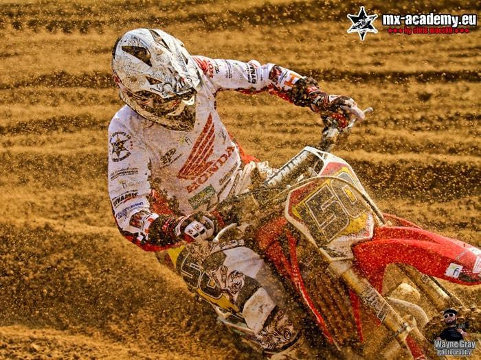 Motocross Sport in der Praxis: Fahrer legt seine Honda in einer Kurve der Strecke schräg
