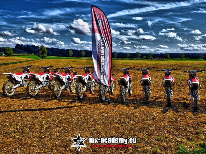 Mietmotorräder in einer Reihe neben der Fahne – Crossmotorrad mieten in der MX-Academy