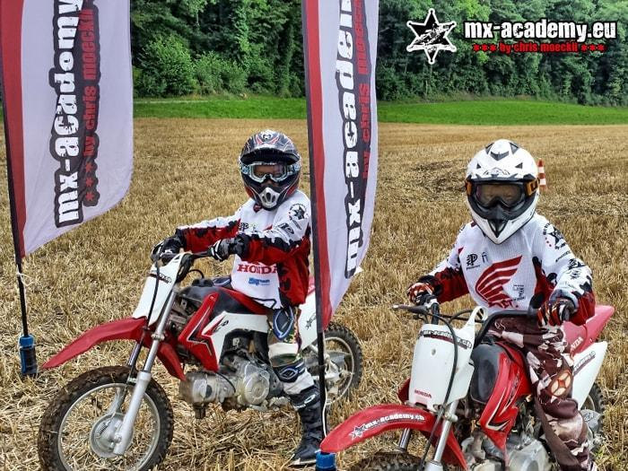 Zwei junge Fahrer auf Kinderbikes vor den Fahnen – Motocross Sport für Kinder und Jugendliche