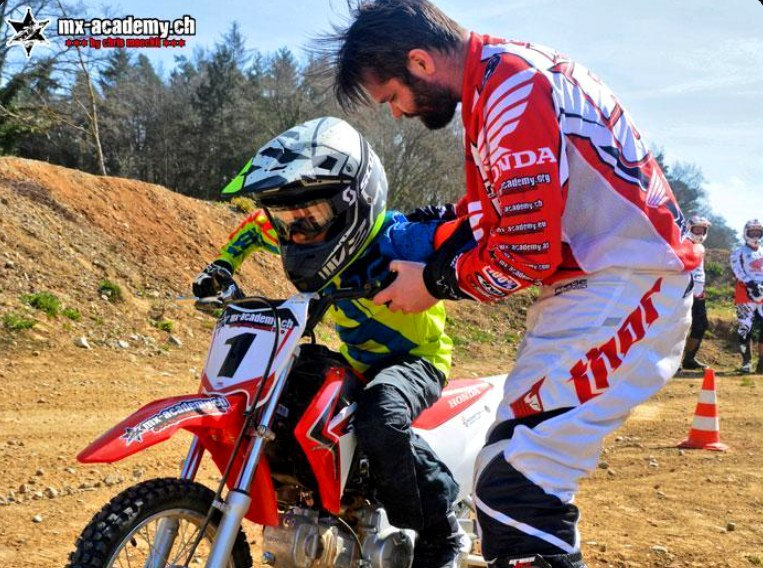 Motocross Schnupperkurs für kleine Kinder: Trainer hilft einem Kind auf dem Bike