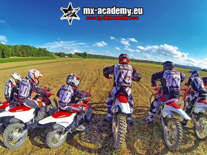 Gruppe Fahrer mit ihren Motorrädern auf dem Feld – das Motocross Team der MX-Academy