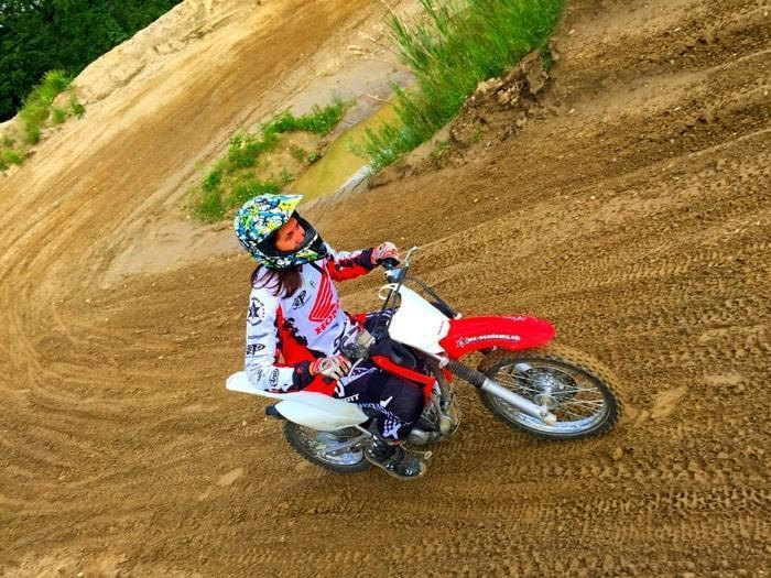 Fahrerin mit buntem Helm fährt durch die Steilkurve – Motorrad Frauen-Kurs der MX-Academy